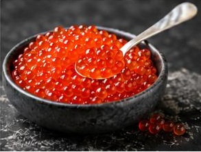 Red caviar presented in a dark bowl